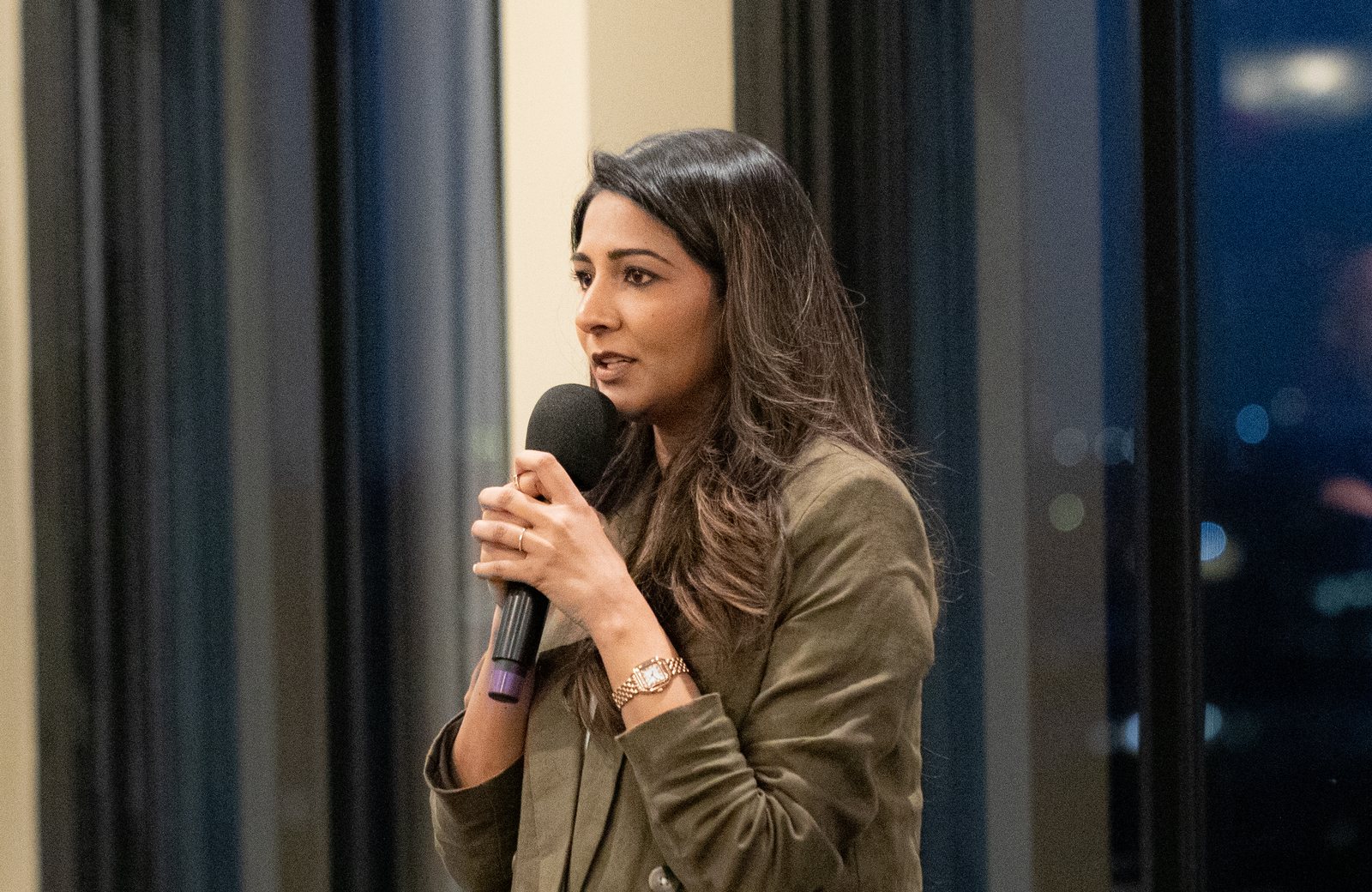 Dr. Anum Ali speaking into a microphone at an evening event